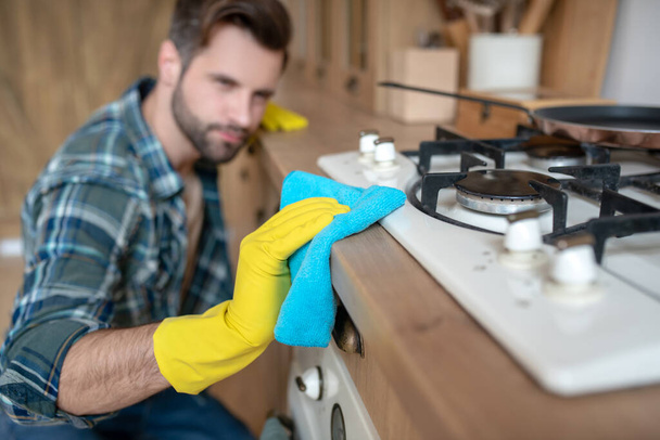 Man in yellow gloves cleaning the surface in the kitchen - Foto, Bild