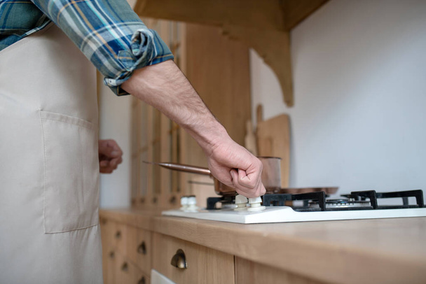 Man in a checkered shirt putting the pan on the oven - Fotó, kép