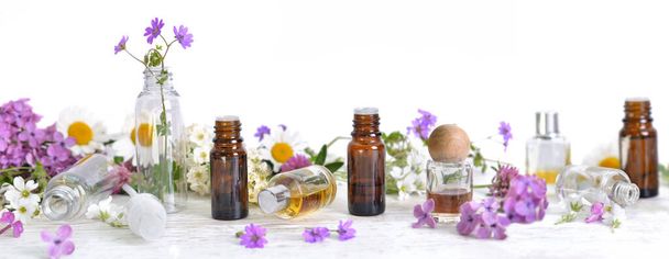 bottles of essential oil and fresh flowers on white background - Photo, Image