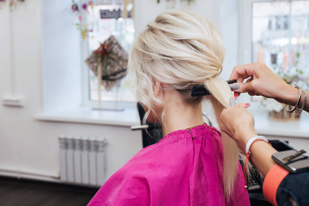 ręce profesjonalnego fryzjera zrobić fryzurę dla blondynki z długimi włosami - Zdjęcie, obraz