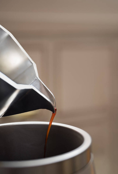 Close up of pouring out coffee from moka pot in a big metal thermo cup. Morning with espresso. - Foto, Imagen