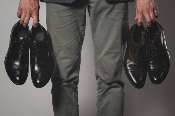 Businessman is choosing a new footwear between brown or black shoes. - Foto, Imagen