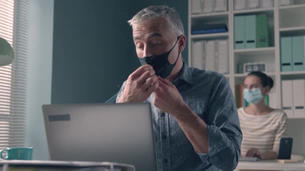 Pracownik biurowy noszący maskę i mający problemy z oddychaniem - Materiał filmowy, wideo