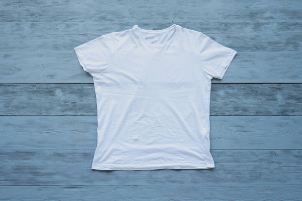 White t shirt on a blue wooden floor background. - Zdjęcie, obraz