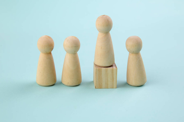 Wooden figure standing on the box for show influence and empowerment on blue background. Concept of business leadership for leader team - Photo, Image
