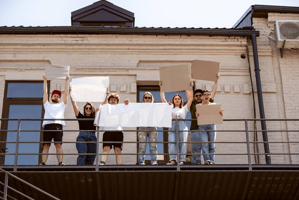 空白の看板に抗議する多様な人々のグループ。人権、自由の乱用、社会問題に対する抗議 - 写真・画像