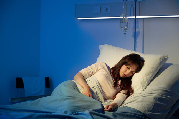 Young woman lying in a hospital bed at night and sleeping  - Photo, Image