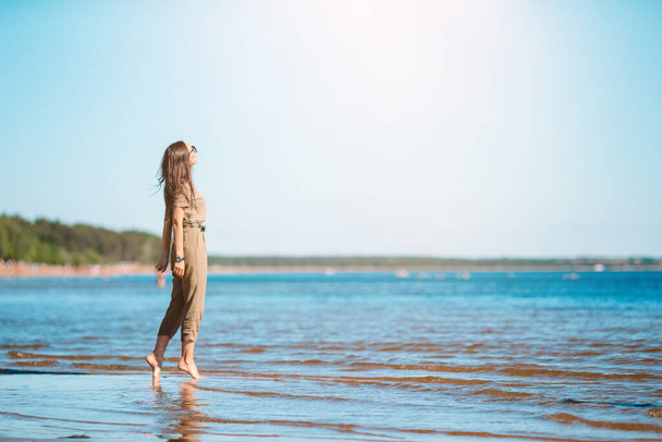 Νεαρή όμορφη γυναίκα διασκεδάζει στην τροπική ακτή. - Φωτογραφία, εικόνα