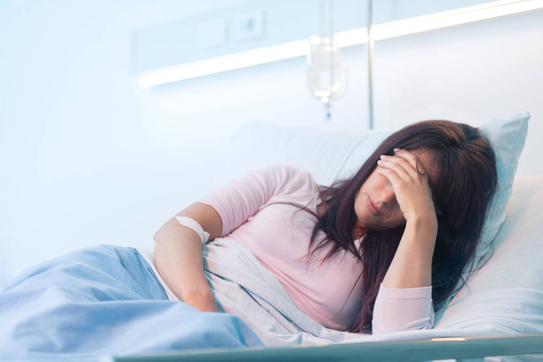Giovane paziente donna sdraiata in un letto d'ospedale di notte e lei sta soffrendo - Foto, immagini