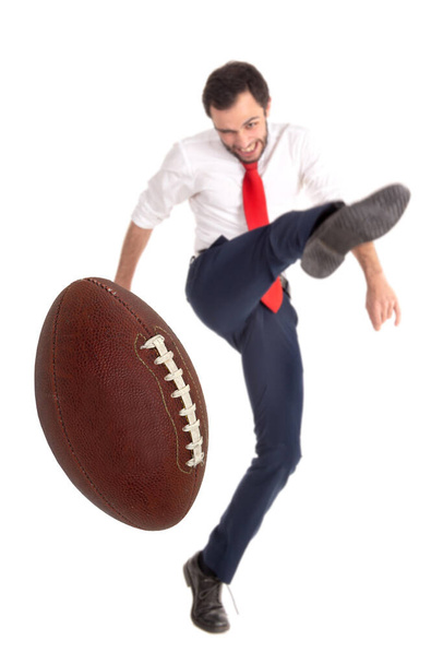 Empresario pateando aa pelota de fútbol americano o pelota de rugby aislado en blanco - Foto, Imagen
