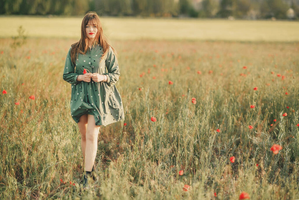 Girl in a green dress with a guitar in a poppy field - Foto, Imagen