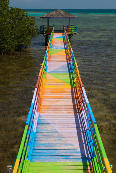 鮮やかな色で飾られた木製の遊歩道,海に面したとマングローブの間で,若井市,トーゲン諸島,インドネシア.. - 写真・画像