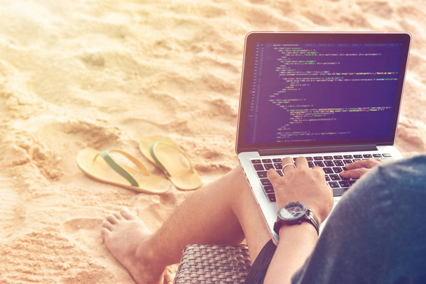 Un programmeur tapant des codes sources à la plage dans un environnement de travail relaxant. Etudier, Travailler, Technologie, Travail indépendant Concept. - Photo, image