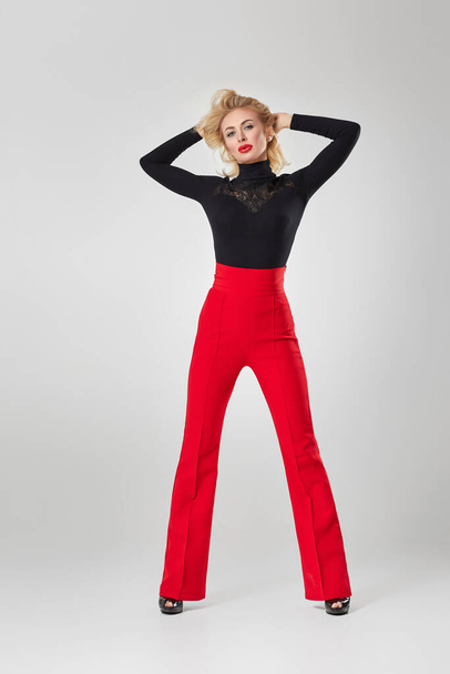 blonde woman in black shirt and red pants - Foto, Imagen