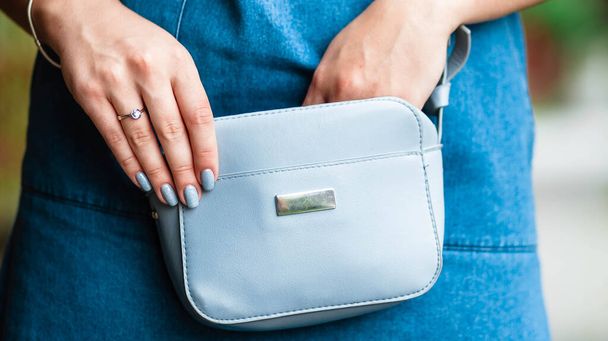 Woman's hand keeping her smartphone in her handbag while. Selective focus. Handbag. Bag in women's hands. - Фото, зображення