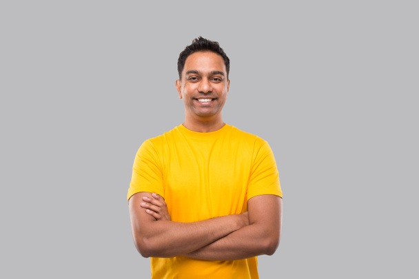 Індійський чоловік стоячи руки перехрещений посміхаючись у жовтій сорочці Ізольований. Людина - Фото, зображення