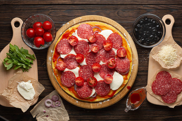 Process of making homemade pizza with mozzarella olives and salami - Photo, Image