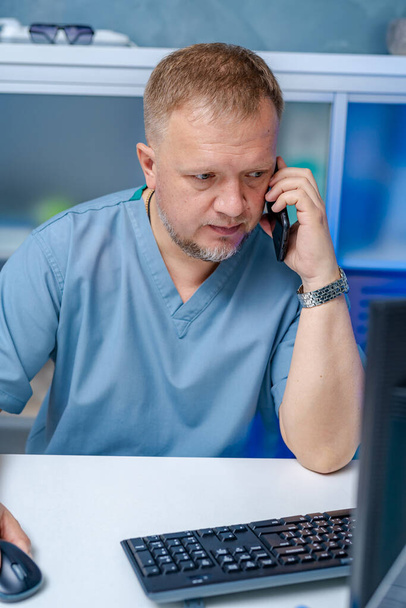 Doctor in medical office. Medical worker talking on thephone near computer. medical concept. - Foto, Imagen