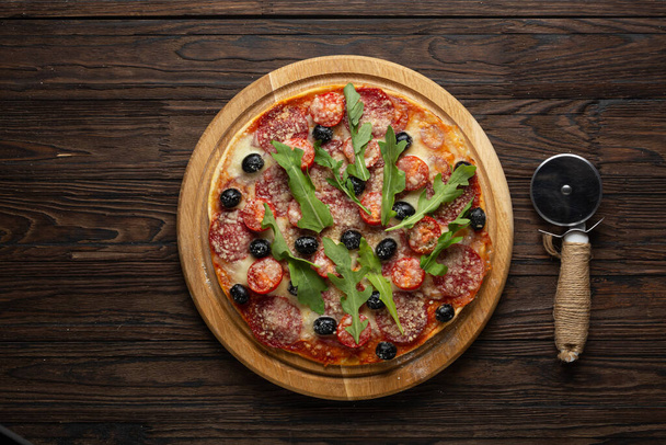 Proceso de hacer pizza casera con aceitunas de mozzarella y salami
 - Foto, imagen