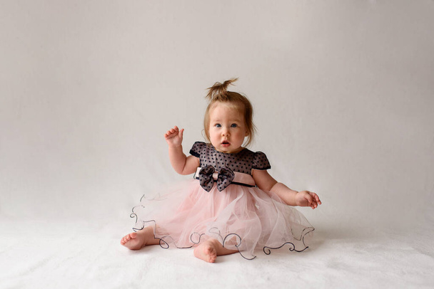 Little girl in a dress sits on a white background. - Photo, Image