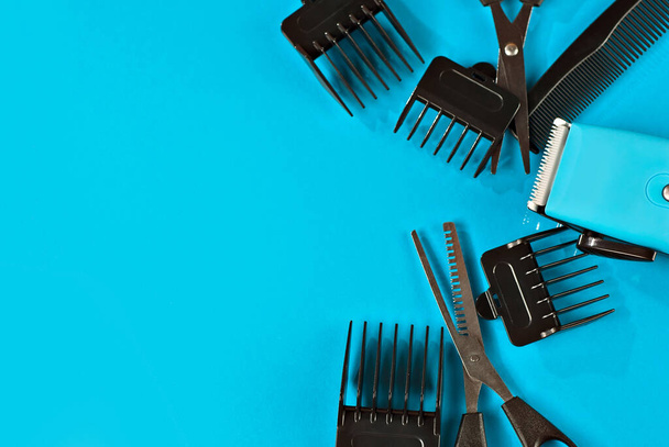 Haircut accessories on a blue background. Haircut machine with different attachments and scissors. Layout for design. Copy space and space for text near tools. - Foto, Imagem