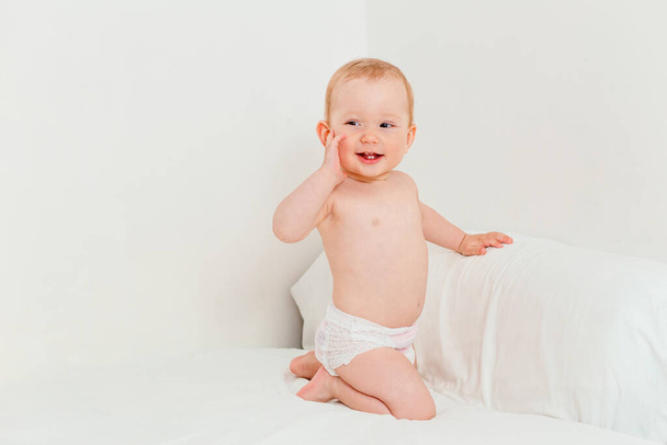 Bébé souriant seulement dans une couche sur un fond blanc - Photo, image