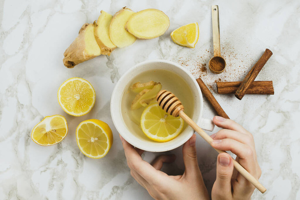 Flatlay of healthy drink with lemon, fresh ginger root, cinnamon sticks and agave syrup on marble background, natural cold or sore throat - Foto, immagini