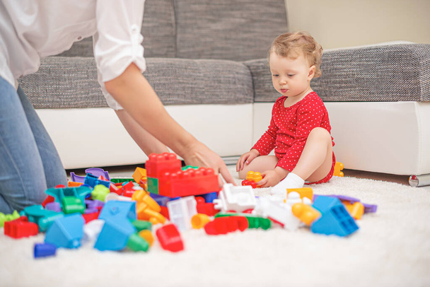 Child girl with mom play in multi-colored toy blocks and cubes. - 写真・画像