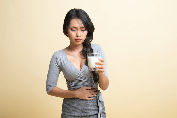 Asian woman drinking a glass of milk got stomachache   on beige background - Foto, afbeelding