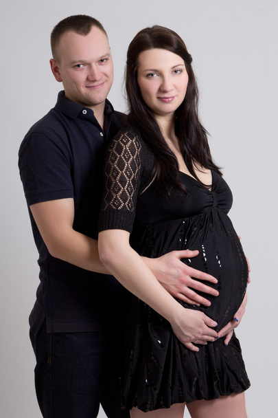 young beautiful pregnant woman with husband over grey - Фото, изображение