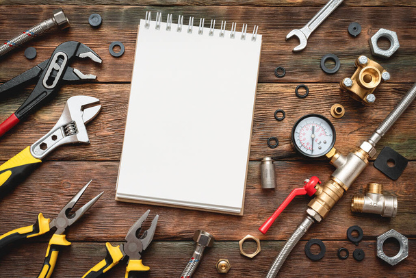 Plumbing flat lay background with copy space. Work tools, pipeline equipment and blank page notepad on plumber workbench. Fix list mockup. - Foto, Bild