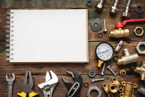 Plumbing flat lay background with copy space. Work tools, pipeline equipment and blank page notepad on plumber workbench. Fix list mockup. - Foto, imagen