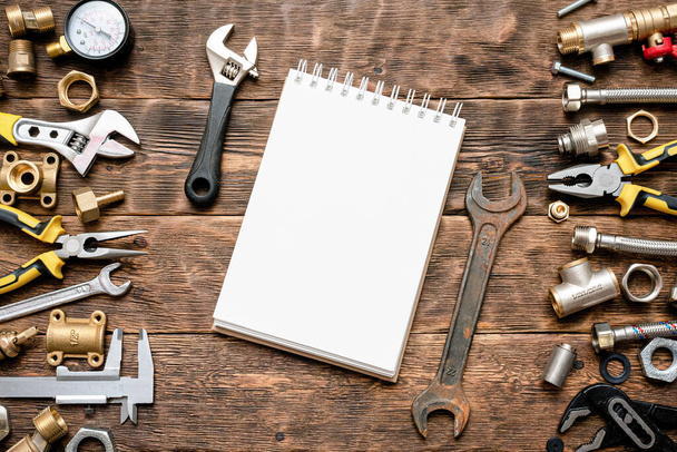 Plumbing flat lay background with copy space. Work tools, pipeline equipment and blank page notepad on plumber workbench. Fix list mockup. - 写真・画像