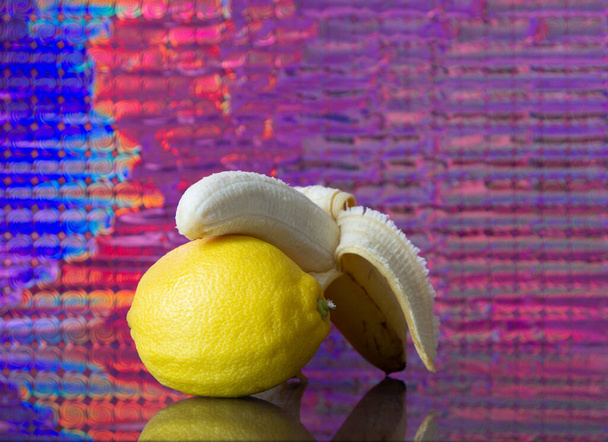 fruits on the mirror bananas, cherry, lemon with a colored background - Valokuva, kuva