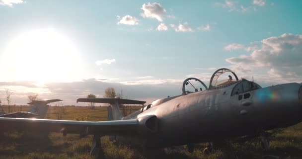 Vue rapprochée de deux avions de chasse militaires soviétiques de la Seconde Guerre mondiale sur le terrain sur fond de grand soleil et de nuages brillants en été. Avion bombardier cassé dans l'ancien aérodrome abandonné. - Séquence, vidéo