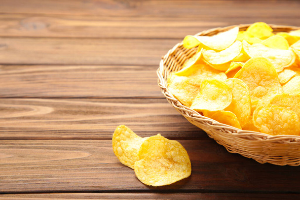 Potato chips in basket on brown wooden background. Top view - Photo, image