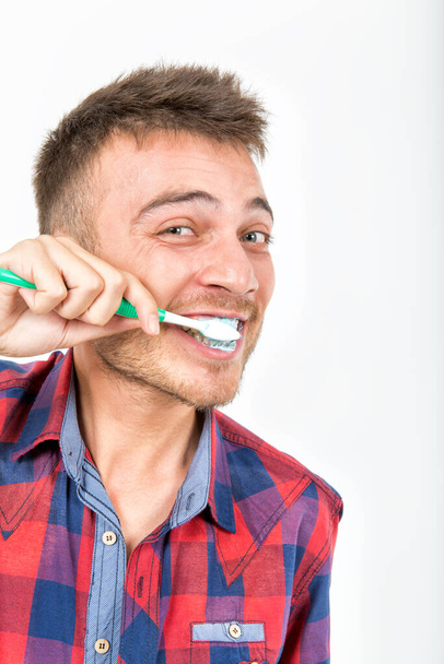 a young man in a plaid shirt brushing his teeth. happy and positive - Fotoğraf, Görsel