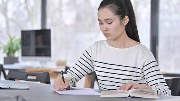 Young Asian Woman Doing Paperwork with Book in Office - Photo, Image