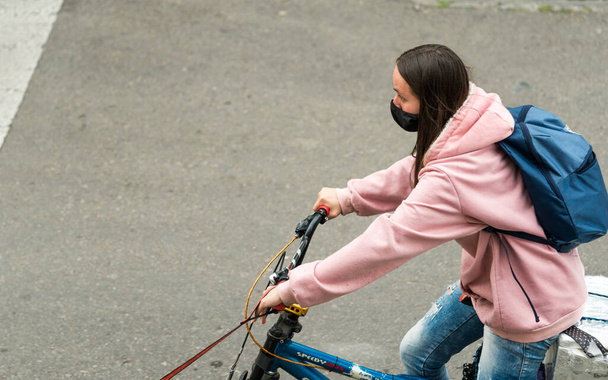 Joven ciclista con máscara; montando su bicicleta en las calles de Bogotá, Colombia. Evite la captura y propagación del coronavirus. Mujer con sudadera y mochila
. - Foto, imagen