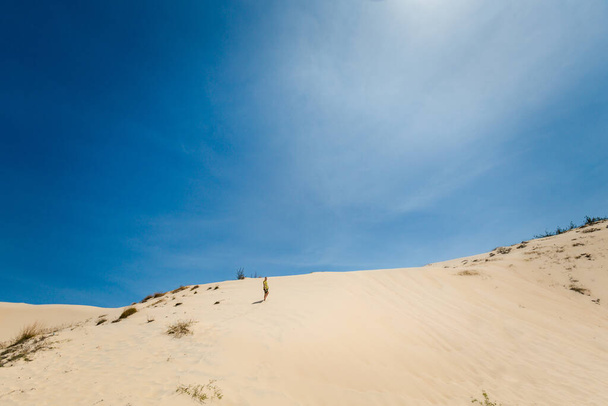 Nuori komea mies pitää hauskaa White hiekkadyynit La Gi, Phan Tiet alueella Vietnamissa. Maisema sininen taivas eteläpuolella Mui Ne. - Valokuva, kuva