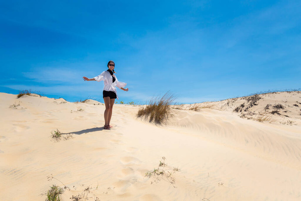 Beautiful caucasian girl having fun on White sand dunes in La Gi, Phan Tiet area in Vietnam. Landscape with blue sky on the south of Mui Ne. - Фото, изображение