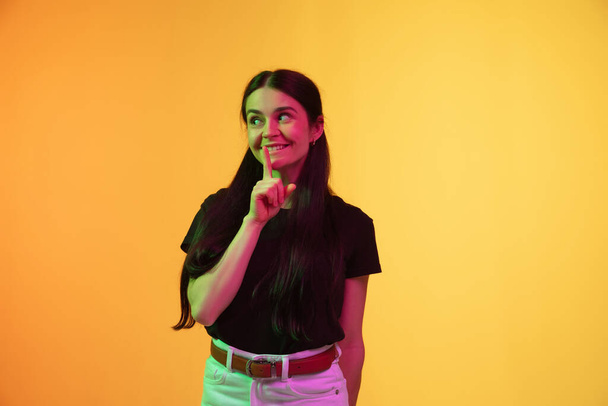 Caucasian young womans portrait on yellow background in neon light - Photo, image