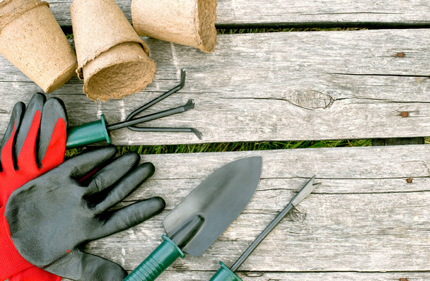 Садові інструменти, рукавички та торф'яні чашки для розсади на дерев'яному тлі. Концептуальне зображення садового обладнання
. - Фото, зображення
