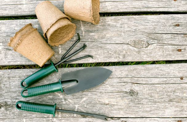 木製の背景に苗のためのガーデンツールと泥炭カップ。庭用機器のコンセプトイメージ. - 写真・画像