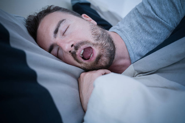 Man snoring loudly in his bed during night time - Foto, Bild
