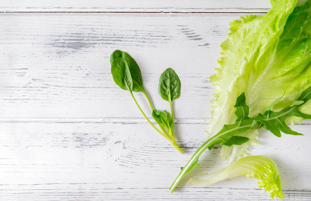 lettuce, arugula leaves, green  spinach, herbs on a white wooden background, close up - Valokuva, kuva