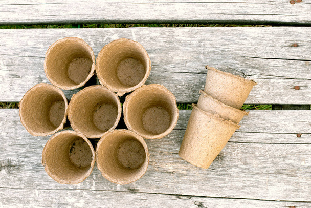 Торфяные чашки для саженцев на деревянном фоне. Концептуальный образ садового оборудования с
. - Фото, изображение