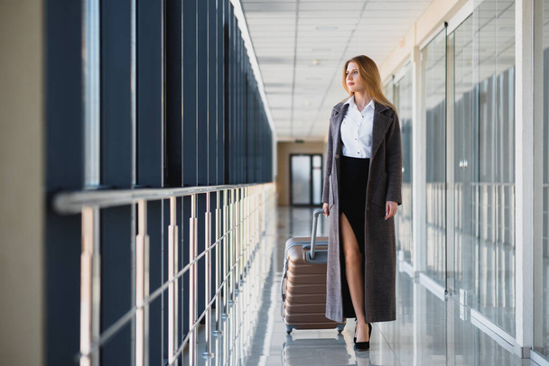 Portrait of successful business woman traveling with case at airport. Beautiful stylish female travel with luggage. - Foto, imagen