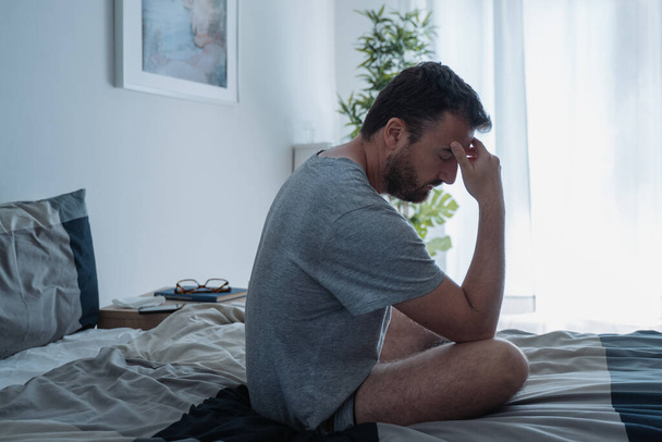 Muž v depresi, sedící na posteli, se cítí špatně - Fotografie, Obrázek