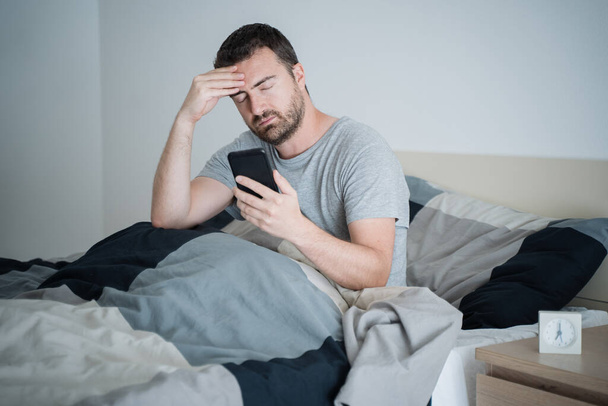 One guy reading bed news on cellphone - Zdjęcie, obraz